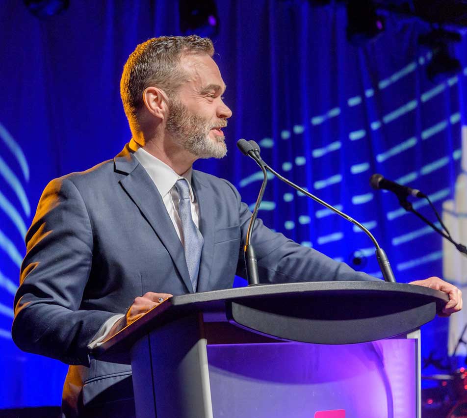A speaker at a podium on an AVentPro-lit stage